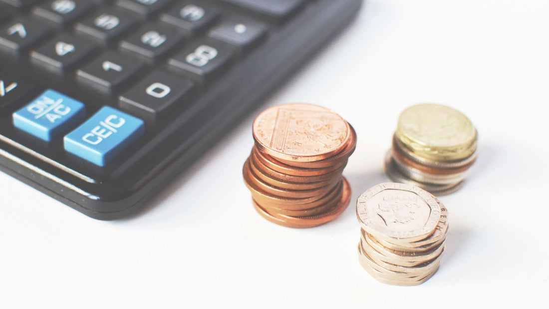電卓と硬貨。巻き爪ケアにかかる費用を1回の値段ではなく総額で計算するイメージ