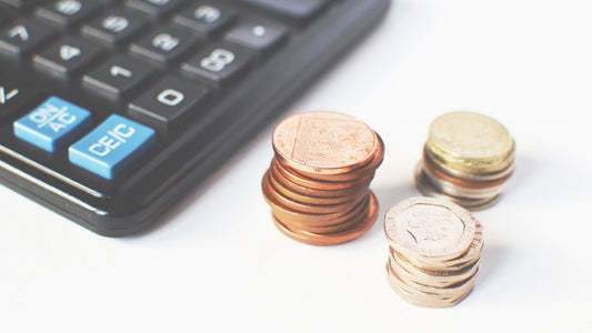 電卓と硬貨。巻き爪ケアにかかる費用を1回の値段ではなく総額で計算するイメージ